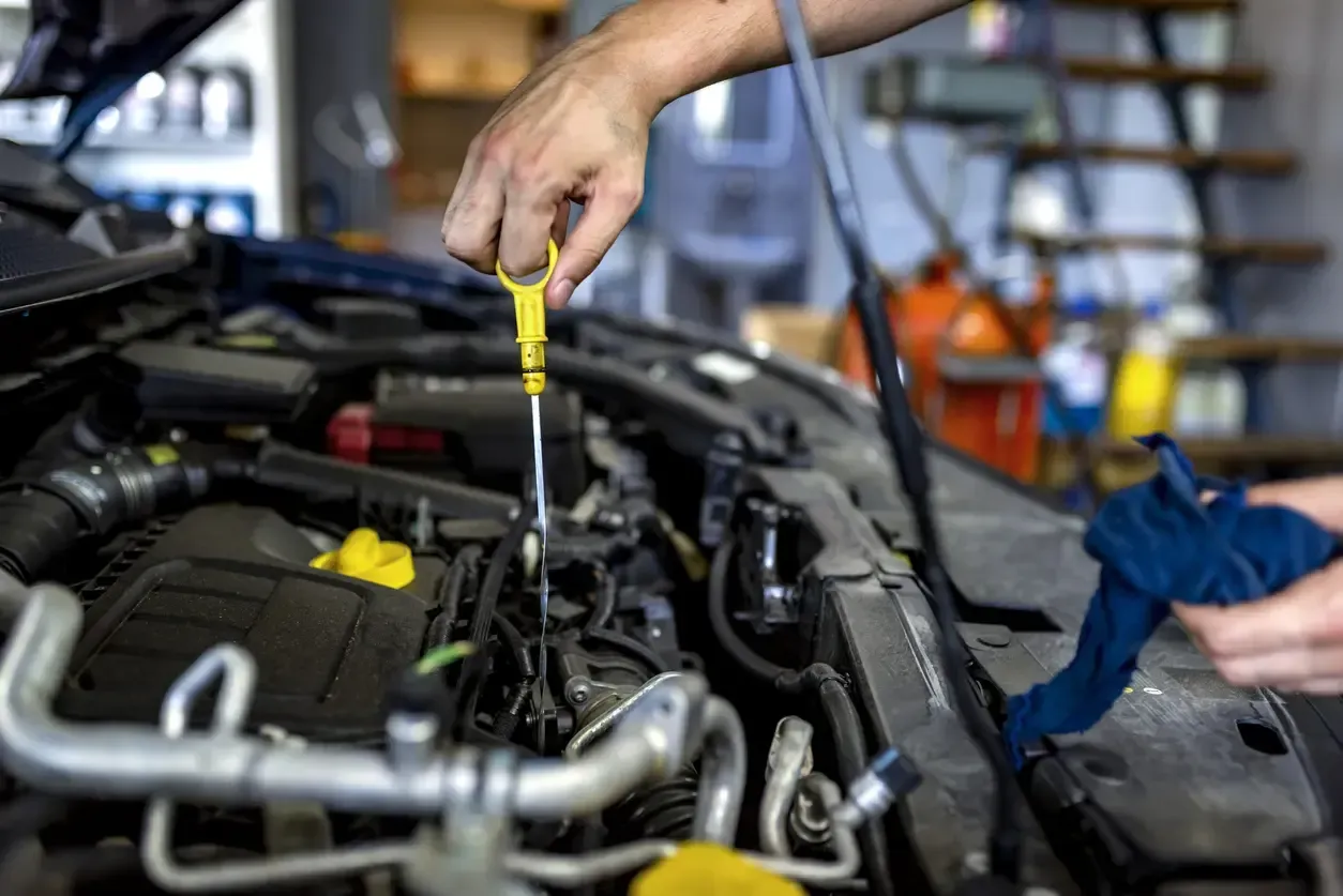 Mechanic checking engine oil level with the yellow dipstick during preventive maintenance